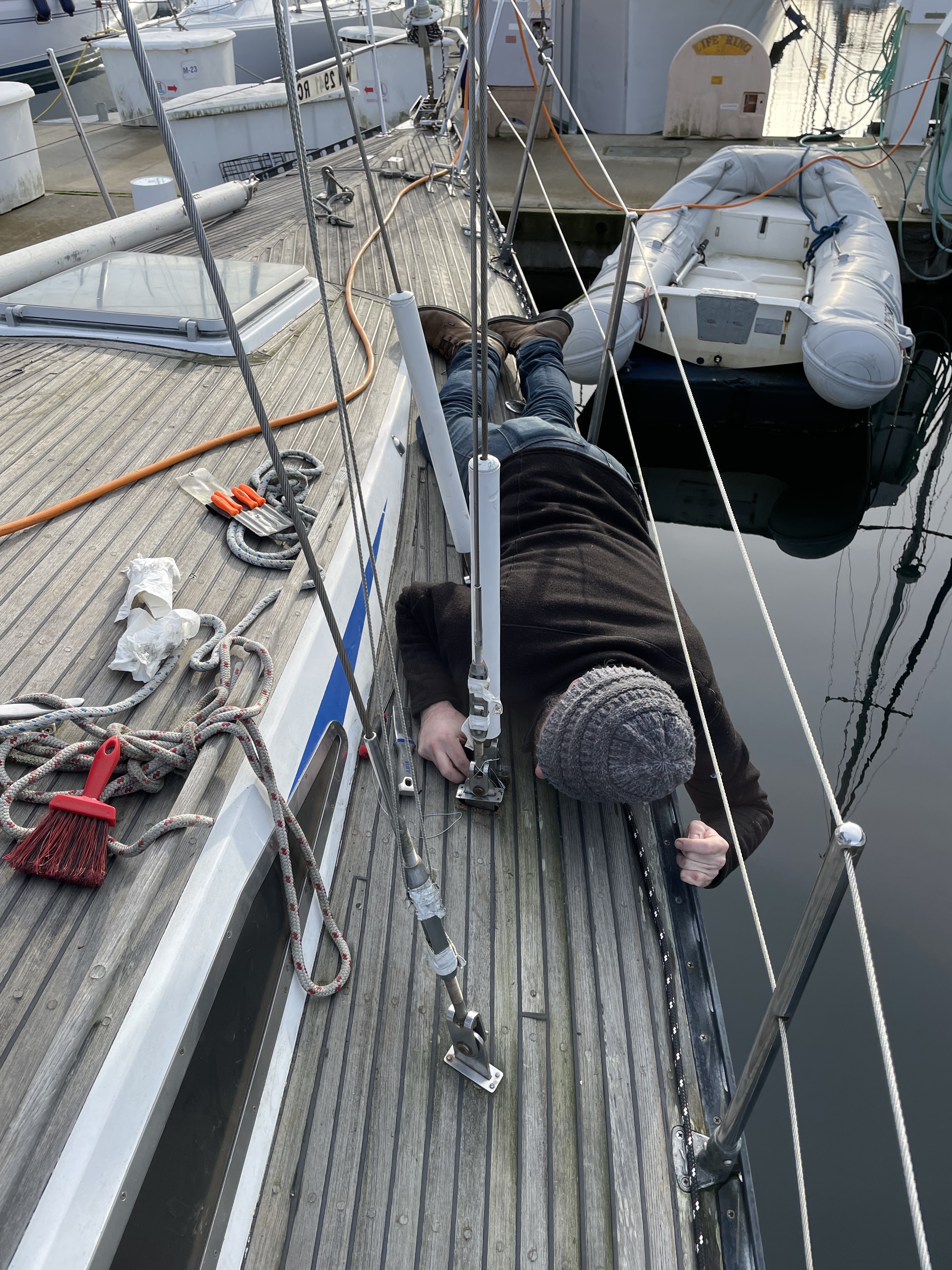 Shane lying down on deck closely inspecting hardware.