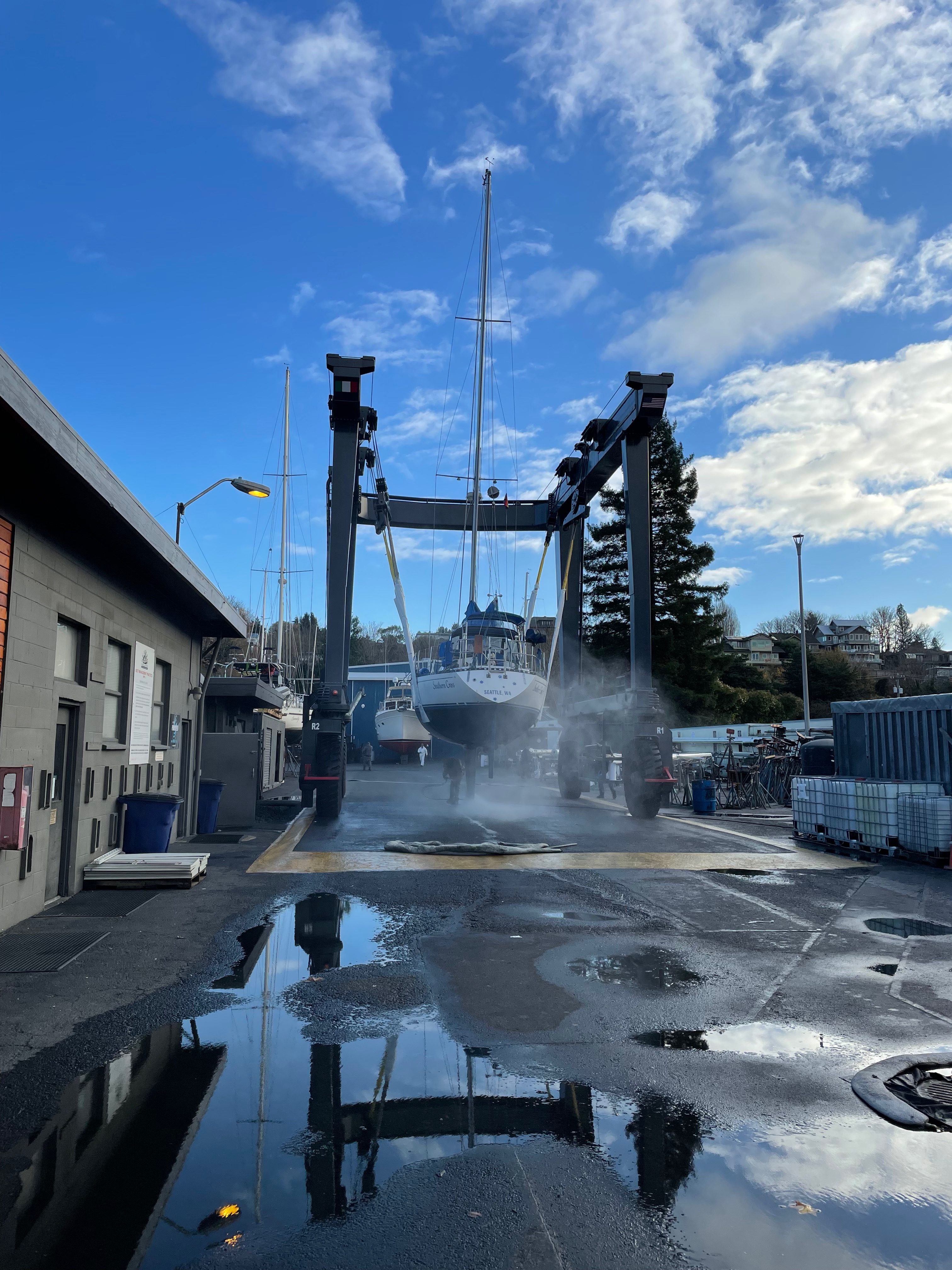 Sailboat in boat hoist getting washed by a power washer