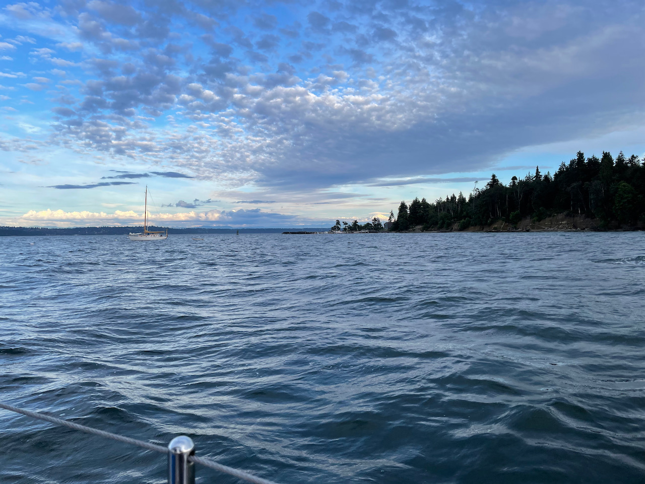 choppy waves, boat moored in the foreground, island with mountain behind it in the background