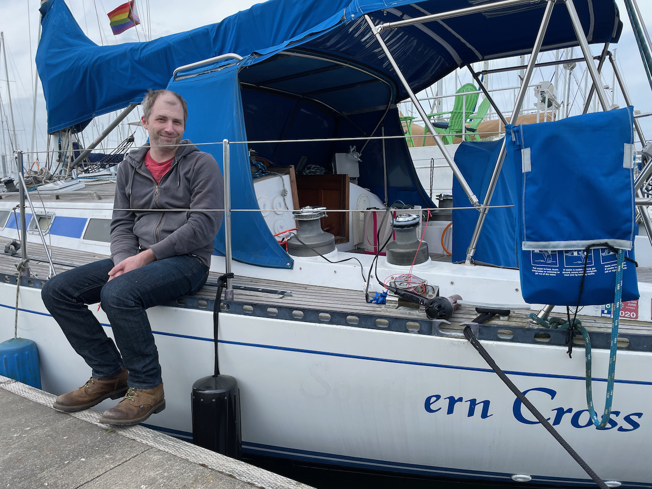 Shane seated on the boat, next to partially removed vinyl lettering