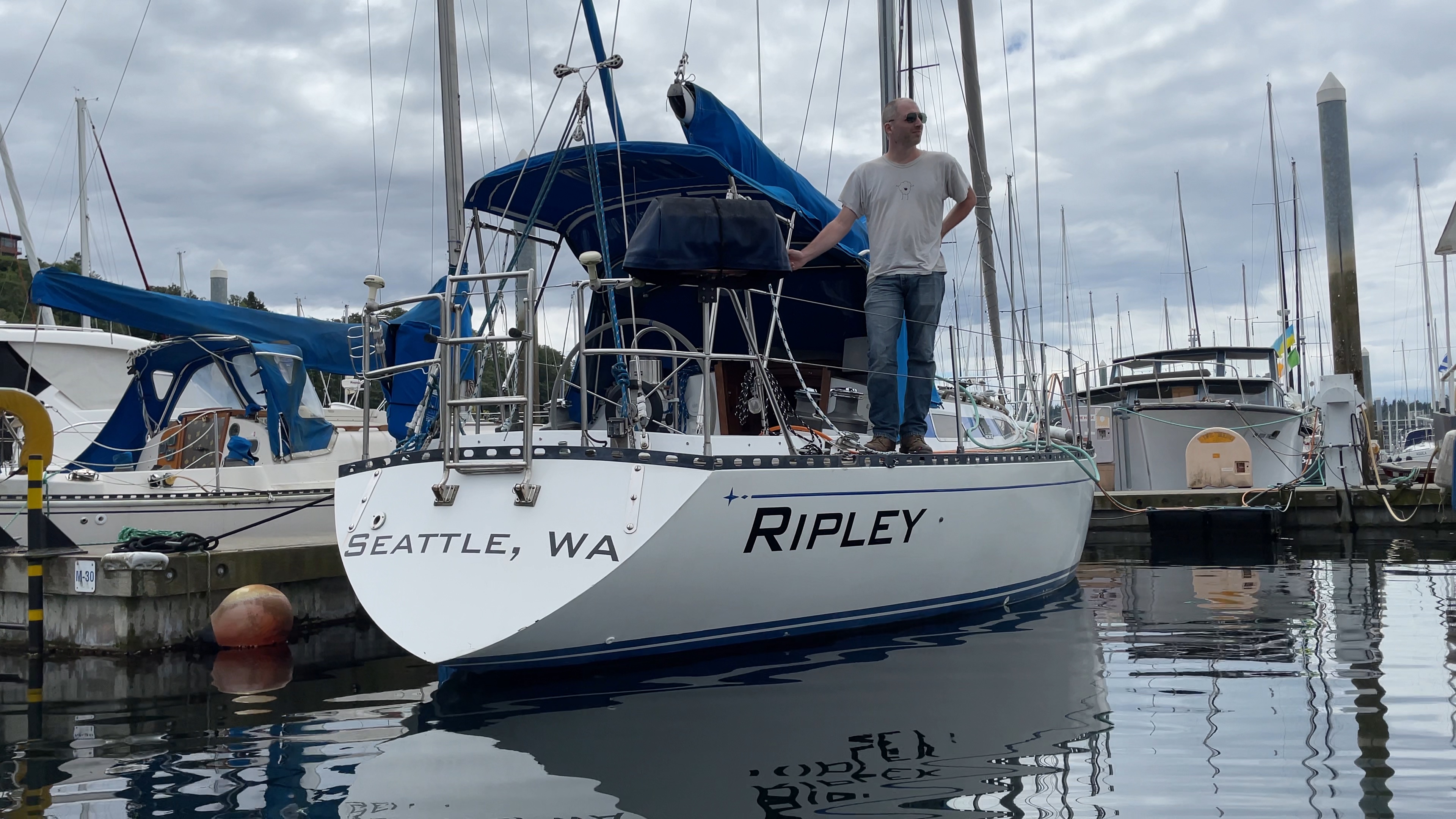 Ripley at the dock, from behind, with Shane standing on the deck, looking off into the distance.